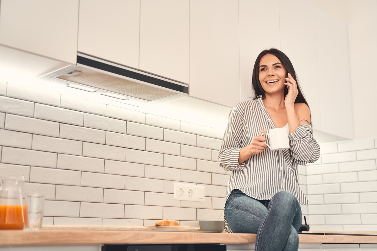 mujer habla por movil en cocina iluminada